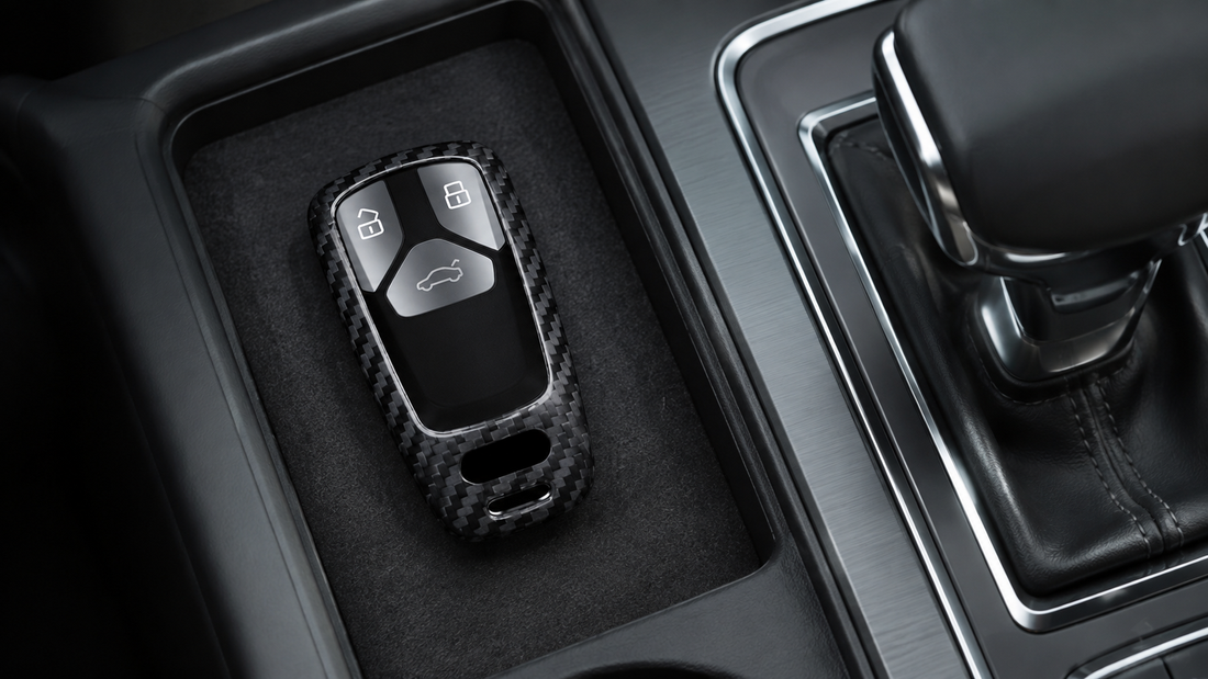 Carbon fiber Audi wide-key fob cover resting in a felt-lined center-console storage tray