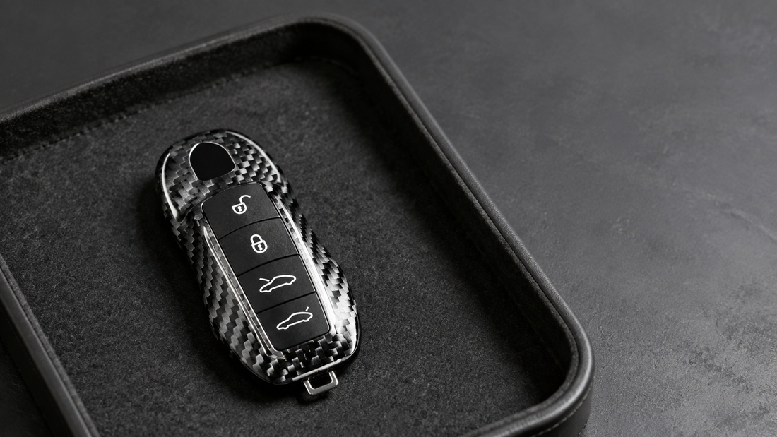 Carbon fiber Porsche key fob cover resting in a charcoal felt key tray